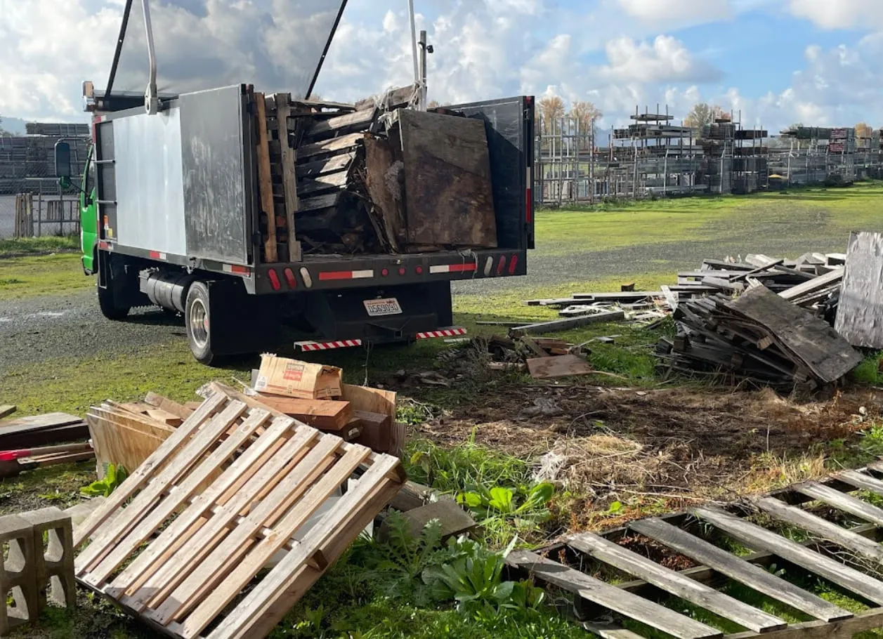 The truck loaded with construction debris beside a stack of wooden pallets